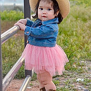Arianna is registered to the contest to win money with this photo: toddler, child, cowboy_hat, denim_jacket, pink_tutu, cowboy_boots, outdoor, fence, grass, dirt, curious, standing, young_child, nature, casual_clothing, portrait, cute, baby, person, daylight