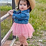 toddler, child, cowboy_hat, denim_jacket, pink_tutu, cowboy_boots, outdoor, fence, grass, dirt, curious, standing, young_child, nature, casual_clothing, portrait, cute, baby, person, daylight