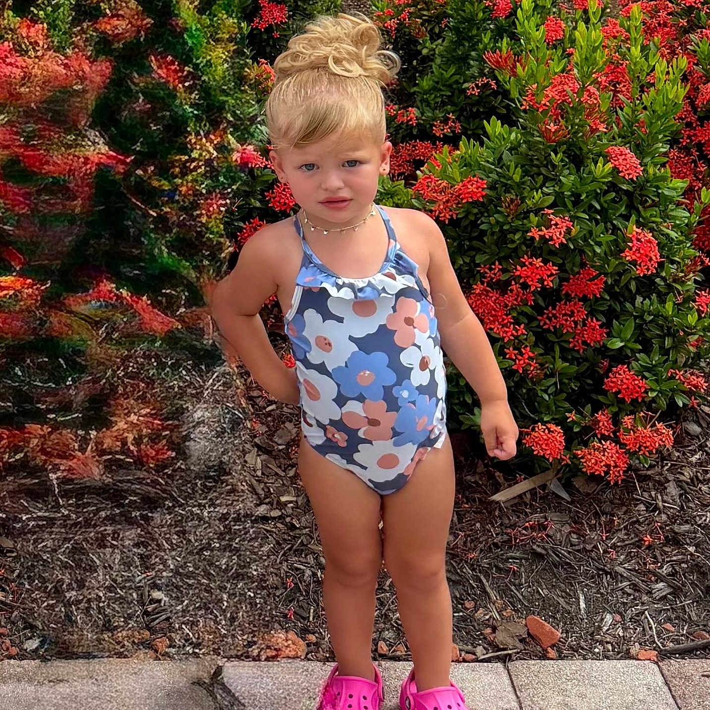 Margaux joined the competition — help win amazing prizes! casual, child, confident, daylight, flower_pattern, garden, girl, greenery, hair_bun, nature, outdoor, pink_crocs, plants, portrait, red_flowers, sidewalk, standing, summer, swimsuit, young_child