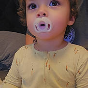 Domenick joined the competition — help win amazing prizes! toddler, child, pacifier, curly_hair, pajamas, carrot_print, indoor, portrait, cute, young_child, expression, close_up, face, person, sitting, home, cozy, clothing, soft_light, curiosity