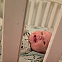 baby, crib, smiling, face, infant, child, sleeping_area, furniture, bars, happy, closeup, person, indoors, cute, expression, soft, blanket, clothing, head, portrait