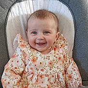 Nina a rejoint le concours — aidez-le/la à gagner de superbes lots ! baby, smiling, child, face, blue_eyes, floral_dress, infant, cute, happy, seated, cushion, baby_chair, portrait, indoor, clothing, young_child, person, apparel, head, skin