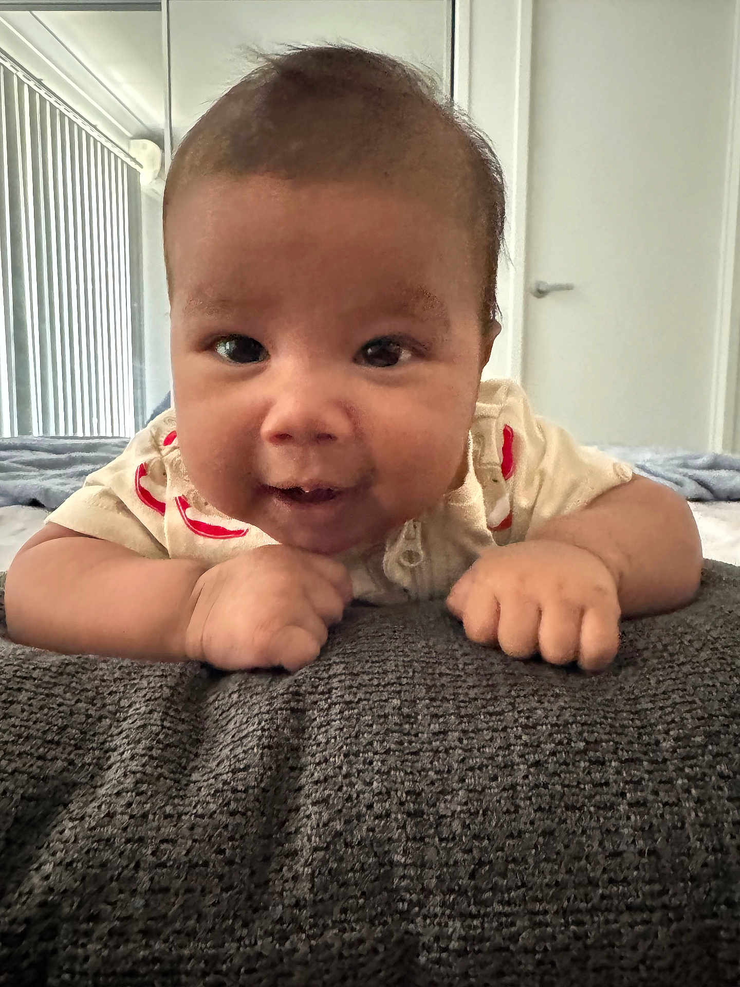 Ruhan Aditiyaa is registered to the contest to win money with this photo: baby, infant, child, face, portrait, close_up, smile, hands, lying_down, blanket, bed, onesie, indoors, mirror, door, window_blinds, cute, grooming, furniture, texture