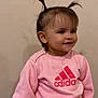 Vaiana participe au concours pour gagner de l'argent avec cette photo : toddler, child, girl, pink_clothing, sweatshirt, pants, pigtails, smile, indoor, wooden_surface, cute, portrait, fashion, casual, adidas_logo, young_child, happy, seated, hair_ties, beige_wall