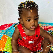 Zakai joined the competition — help win amazing prizes! baby, infant, child, confetti, red_overall, colorful_quilt, curly_hair, sitting, cute, adorable, portrait, indoor, bright_colors, skin, feet, hands, expression, clothing, young_child, face