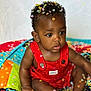 baby, infant, child, confetti, red_overall, colorful_quilt, curly_hair, sitting, cute, adorable, portrait, indoor, bright_colors, skin, feet, hands, expression, clothing, young_child, face