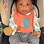 baby, bib, blue_socks, car_seat, child, clothing, curious_expression, cute, dinosaur, grey_pants, holding, indoor, infant, orange_bib, person, plush_toy, portrait, seat, toddler, young_child