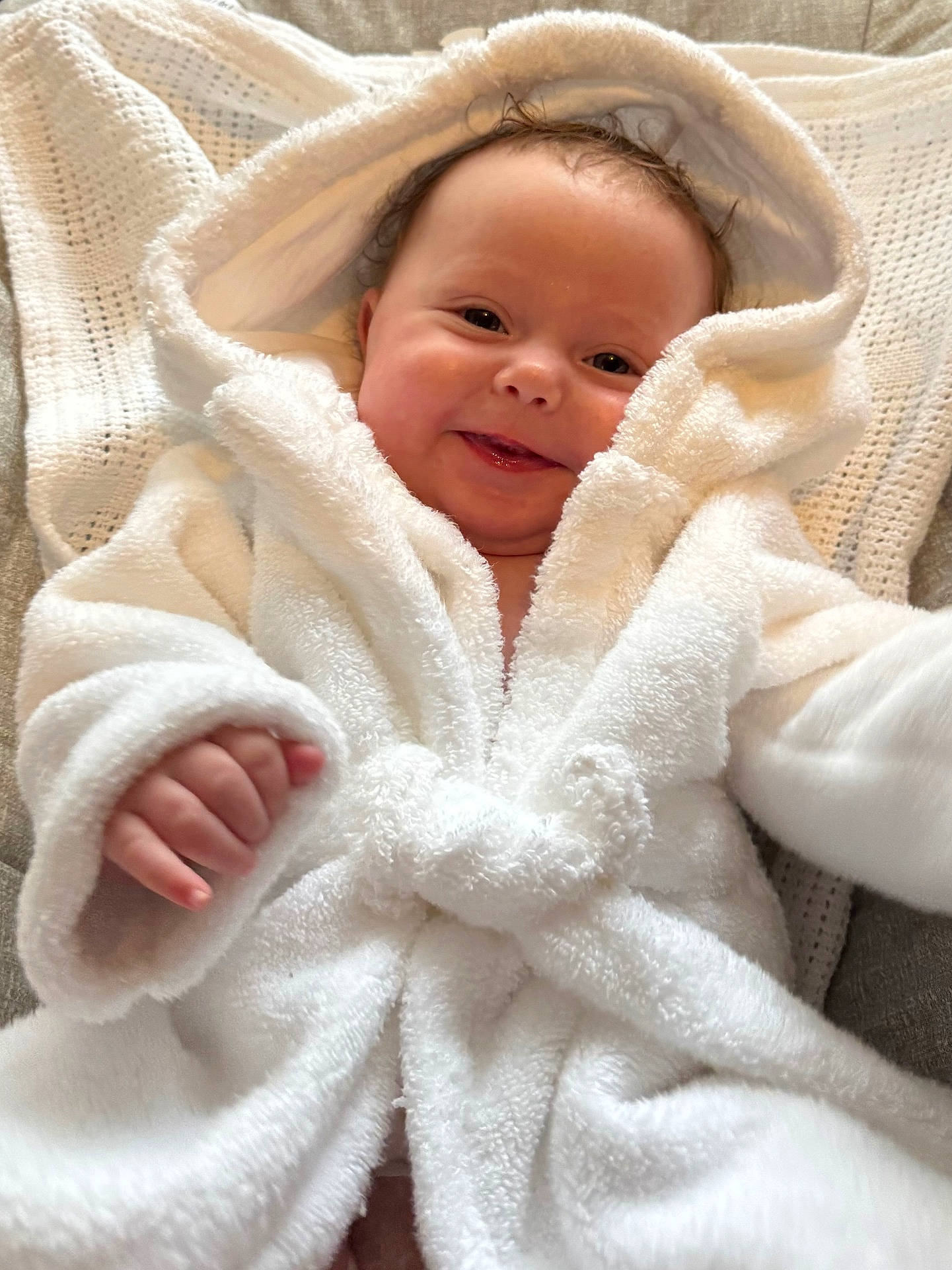 Mabel joined the competition — help win amazing prizes! adorable, baby, blanket, child, comfortable, cozy, cute, face, hand, happy, hood, indoor, infant, lying_down, newborn, portrait, smile, soft_texture, warm, white_bathrobe