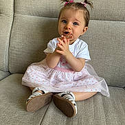 éline a rejoint le concours — aidez-le/la à gagner de superbes lots ! baby, child, clapping, couch, cute, expression, footwear, furniture, hands, indoor, pigtails, pink_skirt, playful, portrait, sandals, sitting, smiling, toddler, white_tshirt, young_child