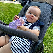Nina-Rose participe au concours pour gagner de l'argent avec cette photo : baby, stroller, sippy_cup, grass, outdoor, child, blue_eyes, striped_clothing, navy_blue, bracelet, cute, sunny, daytime, park, seatbelt, wheels, person, infant, happy, portrait