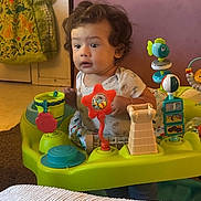Kirill joined the competition — help win amazing prizes! toddler, child, baby, sitting, portrait, curly_hair, facial_expression, indoors, activity_center, baby_toys, colorful, fish_toy, playtime, infant, shirt, home, furniture, carpet, bucket, wooden_door