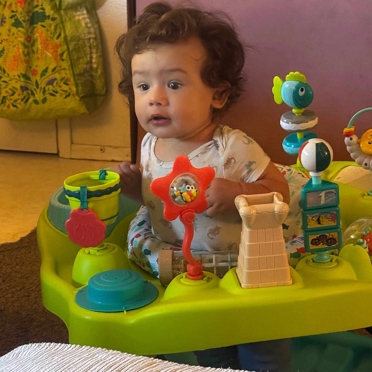 Kirill joined the competition — help win amazing prizes! toddler, child, baby, sitting, portrait, curly_hair, facial_expression, indoors, activity_center, baby_toys, colorful, fish_toy, playtime, infant, shirt, home, furniture, carpet, bucket, wooden_door