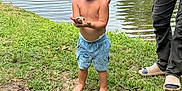 Weston is registered to the contest to win money with this photo: child, toddler, barefoot, fish, pond, grass, water, shorts, shirtless, adult_hand, outdoor, nature, summer, person, fishing, curious, greenery, daylight, recreation, family