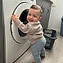 toddler, child, washing_machine, laundry_basket, barefoot, smiling, indoor, flooring, cabinet, clothing, sweater, pants, home, appliance, household, cute, standing, face, happy, person