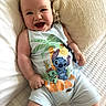 baby, smiling, infant, romper, cartoon_print, bed, pillow, white_bedspread, comfort, happy, child, cute, indoors, person, skin, head, arms, legs, clothing, lying_down