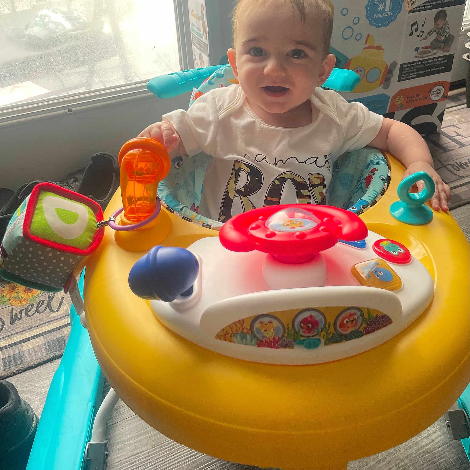 Elijiah is registered to the contest to win money with this photo: baby, child, walker, toy, indoor, smiling, person, face, clothing, colorful, window, floor, box, light, plastic, seat, happy, young_child, play, baby_toys