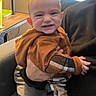 Elijiah joined the competition — help win amazing prizes! baby, child, person, indoor, hoodie, plaid_pants, smile, couch, hand, window_blinds, adult, holding, cozy, casual, furniture, home, warm_lighting, cute, portrait, infant