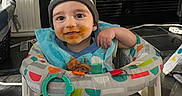 Elijiah is registered to the contest to win money with this photo: baby, child, messy_face, baby_walker, hat, bib, toy, indoor, smiling, cute, colorful, clothing, person, face, happy, sitting, home, floor, playful, infant