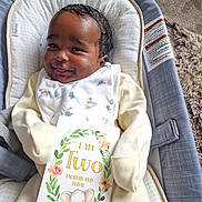Talia-Jane joined the competition — help win amazing prizes! baby, infant, smiling, baby_seat, milestone_card, elephant_illustration, yellow_clothing, white_bib, face, cute, happy, indoor, carpet, baby_accessory, person, newborn, portrait, child, soft_fabric, cozy