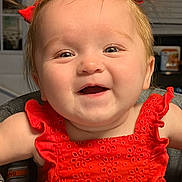 Oakley is registered to the contest to win money with this photo: baby, child, smiling, happy, red_dress, hair_bows, high_chair, reflection, indoor, face, cute, infant, person, portrait, eyes, cheeks, clothing, window_blinds, door, home