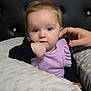 baby, child, face, blue_eyes, hand, blanket, purple_clothing, black_clothing, tufted_background, soft_texture, portrait, indoor, cute, infant, person, sitting, closeup, comfort, gentle_touch, head