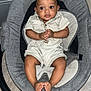 baby, infant, child, baby_rocker, gray_cushion, romper, clothing, hands, feet, floor, indoor, curious_expression, wide_eyes, black_hair, person, sitting, seat, baby_seat, floor_tile, cute