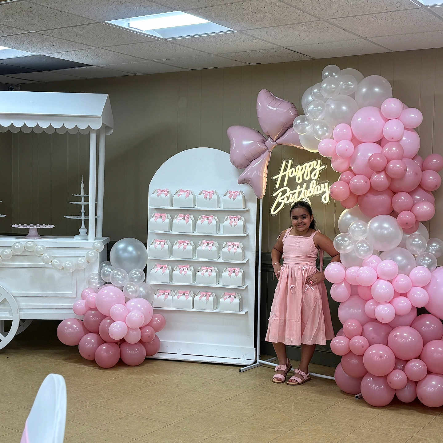 Isabella Rose is registered to the contest to win money with this photo: child, birthday, party, pink_dress, balloons, balloon_arch, birthday_cake, desserts, candy, party_decorations, happy_birthday, indoor, portrait, standing, smiling, gift_boxes, dessert_table, pink, white, celebration