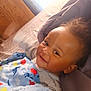 Christopher is registered to the contest to win money with this photo: baby, smiling, blanket, bed, child, indoor, comfort, happy, portrait, person, face, young_child, cozy, cute, soft_light, curly_hair, sleepwear, toddler, resting, warm