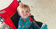 Corbin joined the competition — help win amazing prizes! toddler, child, stroller, red_stroller, space_onesie, smiling, indoor, tile_floor, legs, shoes, candid, playful, baby, person, seat, wheel, footwear, casual, happy, portrait
