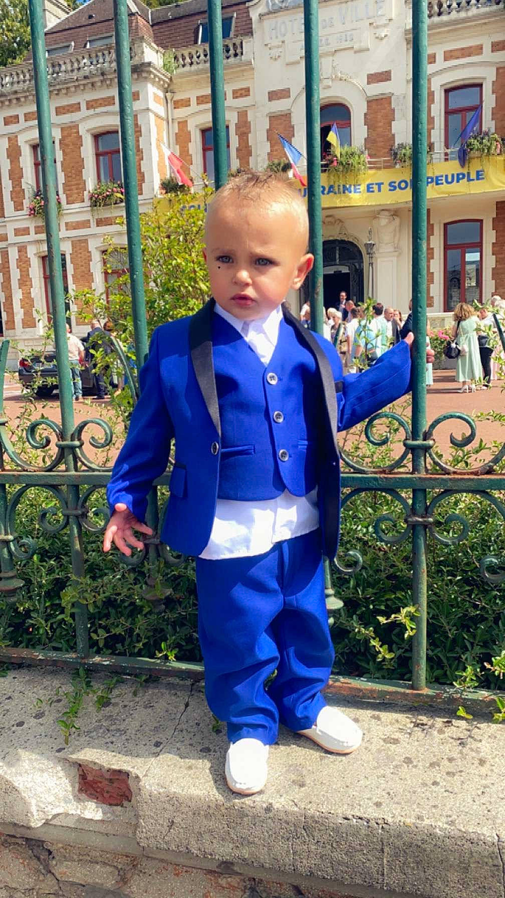 Thyam participe au concours pour gagner de l'argent avec cette photo : baby, baby_toddler_clothing, child, city, costume, denim, electric_blue, fence, formal_wear, fun, grass, leisure, pedestrian, person, plant, sleeve, suit, t_shirt, toddler, uniform