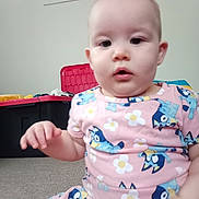 Raven is registered to the contest to win money with this photo: baby, blue_bird_pattern, carpet, casual, child, curious, cute, flowers, indoor, person, pink_dress, portrait, room, sitting, soft_lighting, storage_bins, stuffed_animals, toy, wall, young_child