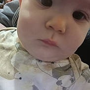 Raven is registered to the contest to win money with this photo: baby, face, close_up, infant, child, onesie, animal_print, indoor, portrait, soft_lighting, curious, young_child, head, skin, clothing, person, expression, cute, young, blurred_background