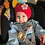 baby, infant, child, car_seat, pacifier, beanie, red_hat, flower_decor, toy_mobile, plush_toy, seatbelt, buckle, smiling, blue_eyes, denim_jacket, rattle, close_up, portrait, indoor, cute