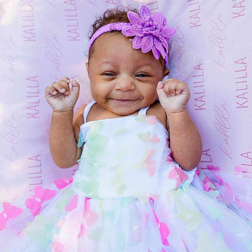 Kalilla is registered to the contest to win money with this photo: baby, blanket, butterfly, child, close_up, curly_hair, custom_print, cute, dress, flower, hands_up, happy, headband, infant, lying_down, name_print, pastel_colors, portrait, smiling, soft_lighting