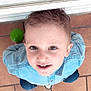 child, boy, smiling, face, denim_shirt, green_ball, floor, tile, casual_clothing, short_hair, indoor, playful, looking_up, cute, portrait, happy, person, childhood, young, casual
