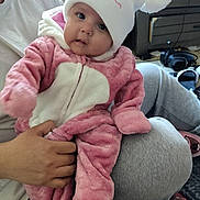 Maylynn Jo joined the competition — help win amazing prizes! baby, child, infant, pink_outfit, white_hat, pom_poms, cute, smiling, indoor, plaid_blanket, person, hand, face, clothing, cozy, floor, furniture, window, casual, home