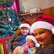 Amara joined the competition — help win amazing prizes! baby, bottle, child, christmas_tree, cute, family, festive, happy, holding, holiday, indoor, red_curtain, santa_hat, seasonal, smile, sweater, toddler, together, warm_lighting, wood_paneling