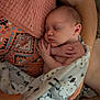 baby, newborn, sleeping, blanket, patterned_blanket, hands, crossed_hands, adult_arm, colorful_clothing, soft_texture, cozy, closeup, infant, peaceful, resting, skin, person, cuddle, indoor, family