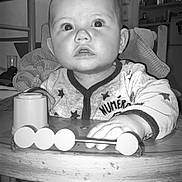 Gabriel participe au concours pour gagner de l'argent avec cette photo : baby, black_and_white, child, closeup, curious, expression, face, furniture, hand, high_chair, indoor, infant, kitchen, pajamas, person, seatbelt, stars, table, toy, wood