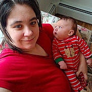 Aurora joined the competition — help win amazing prizes! adult, baby, indoor, smile, red_clothing, striped_pajamas, reindeer_design, curious_baby, couch, floral_pattern, heater, window, person, holding_baby, portrait, casual, home, wood_floor, family, cozy