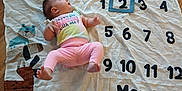 Aurora is registered to the contest to win money with this photo: baby, infant, milestone_blanket, pink_pants, pastel_shirt, wooden_floor, cartoon_dogs, months, numbers, lying_down, child, cute, milestone, floor, colorful, clothing, baby_girl, pattern, celebration, age_marker