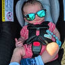 Briar joined the competition — help win amazing prizes! baby, infant, child, car_seat, sunglasses, pink_clothing, striped_shirt, blue_socks, harness, seatbelt, automobile, vehicle_interior, portrait, sitting, sunlight, reflection, pacifier_clip, safety_seat, casual_clothing, funny_pose