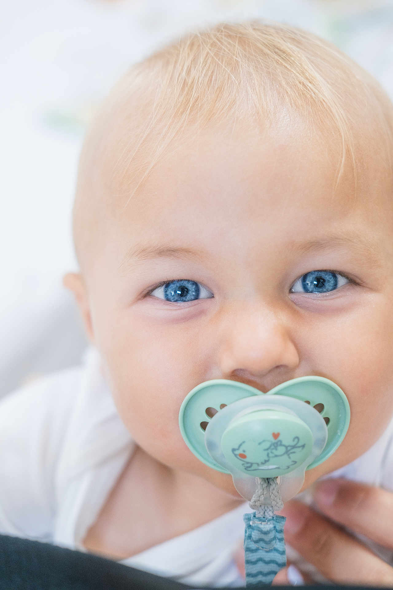 Léon participe au concours pour gagner de l'argent avec cette photo : baby, blue_eyes, pacifier, close_up, infant, cute, child, face, skin, blond_hair, expression, person, young, adorable, mouth, cute_face, pacifier_clip, white_clothing, portrait, hand