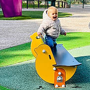 Léon participe au concours pour gagner de l'argent avec cette photo : casual, child, daytime, duck_shape, fun, green_turf, happy, jacket, outdoor, park, person, play, playground, recreation, rocker, smiling, sunlight, toddler, toy, yellow