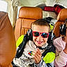 Louis participe au concours pour gagner de l'argent avec cette photo : child, boy, sunglasses, headset, smile, pointing, jacket, hoodie, super_mario, leather_chair, aircraft_interior, window, seat, travel, happy, casual_clothing, playful, person, indoor, transportation