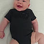 baby, infant, smiling, black_onesie, chubby_cheeks, lying_down, white_background, happy, cute, child, skin, face, arm, leg, person, newborn, expression, joy, indoors, portrait