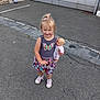 asphalt, blonde_hair, butterfly, casual_clothing, child, curb, doll, dress, girl, hair_bow, happy, outdoor, pavement, person, pink_shoes, play, sidewalk, smiling, toy, urban