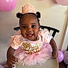baby, child, smiling, high_chair, pink_tutu, birthday_crown, balloons, celebration, party, cute, happy, indoor, person, toddler, curly_hair, pink_clothing, festive, decorations, infant, fun