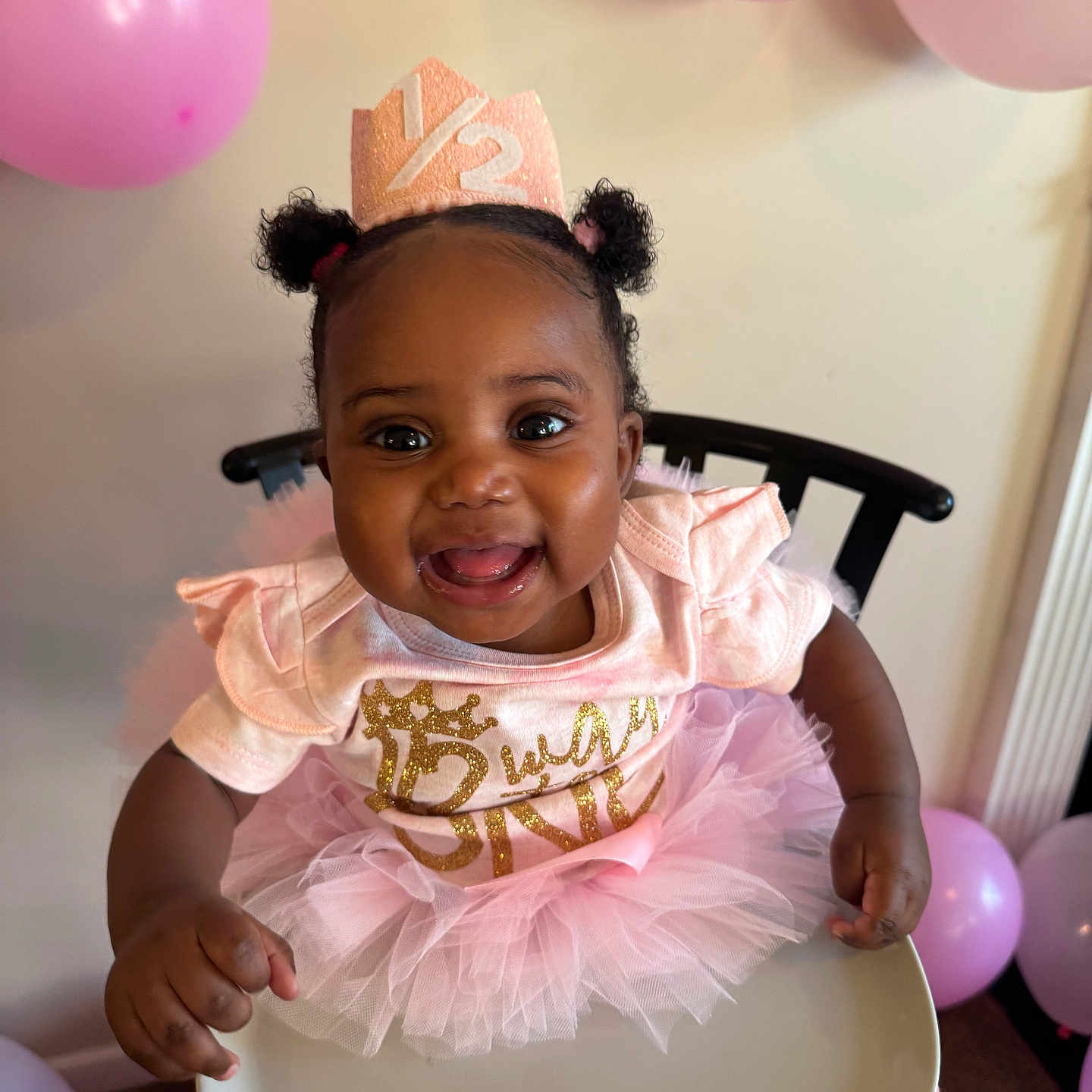 Trinity joined the competition — help win amazing prizes! baby, child, smiling, high_chair, pink_tutu, birthday_crown, balloons, celebration, party, cute, happy, indoor, person, toddler, curly_hair, pink_clothing, festive, decorations, infant, fun