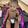baby, diaper, child, person, indoor, lap, purple_cloth, curious, skin, foot, hand, face, expression, blurred_background, sitting, young_child, casual, comfort, home, infant